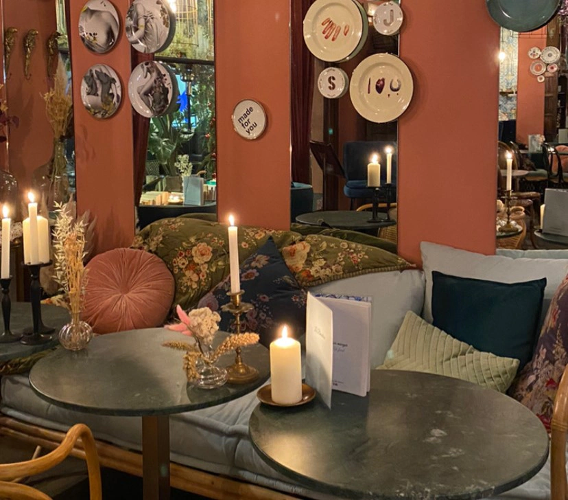 Vraie photographie du Beaulieu : murs terre cuite, banquette fleurie, tables en marbre et bougies