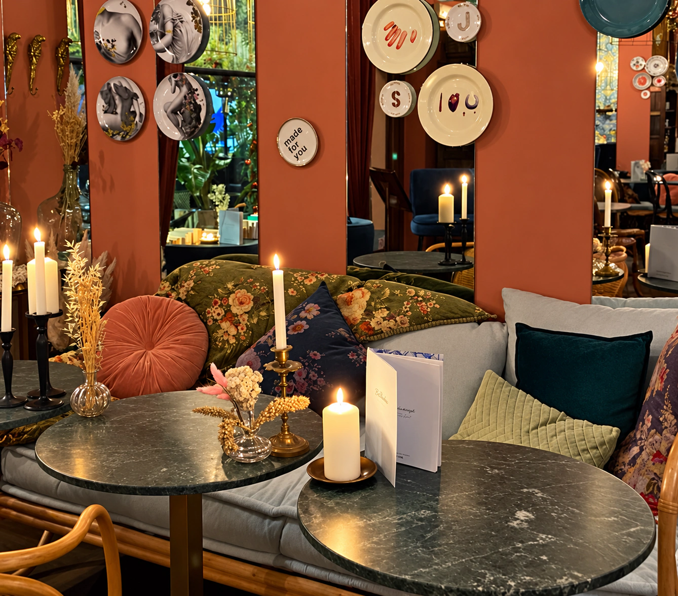 Vraie photographie du Beaulieu : murs terre cuite, banquette fleurie, tables en marbre et bougies