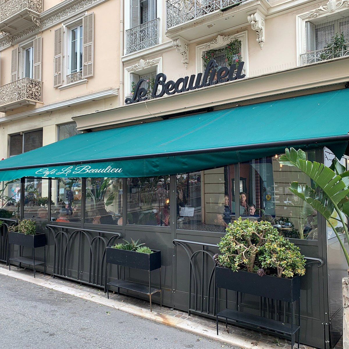 La façade du Café Le Beaulieu avec son store vert et sa terrasse végétalisée